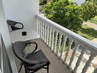 a balcony with a table and two chairs and a white railing at Apartmani Sara in Ulcinj