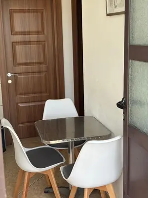 a table and two white chairs and a door at Apartmani Sara in Ulcinj