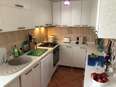 a kitchen with white cabinets and a sink at Axenia Hotel in Utjeha