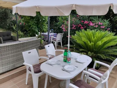 a white table and chairs under an umbrella on a patio at Axenia Hotel in Utjeha