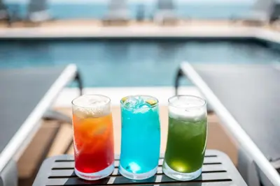 four drinks sitting on a table next to a pool at Plaza Hotel&SPA in Ulcinj