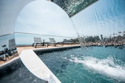 a pool with chairs and a water fountain at Plaza Hotel&SPA in Ulcinj