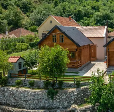 a log cabin with a stone retaining wall at Green Hill in Virpazar