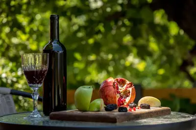 a bottle of wine and a glass on a table with fruit at Green Hill in Virpazar