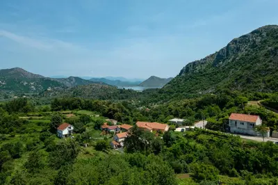 a village on a hill with mountains in the background at Green Hill in Virpazar