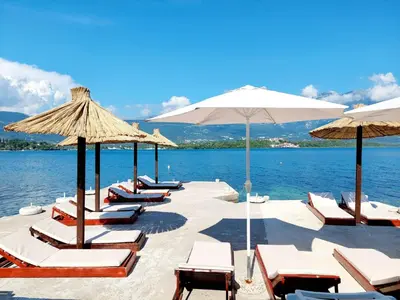 a row of lounge chairs and umbrellas on a beach at Apartments Klakor PS in Tivat