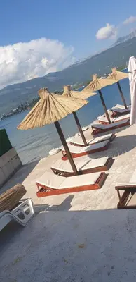 a group of chairs and umbrellas on a beach at Apartments Klakor PS in Tivat