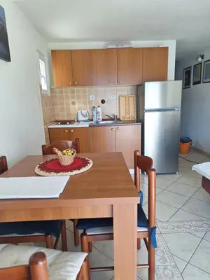 a kitchen with a wooden table and a refrigerator at Apartments Klakor PS in Tivat
