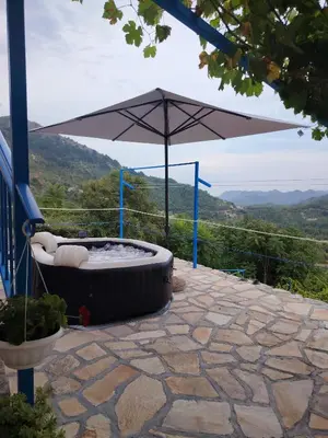 a hot tub with an umbrella on a patio at Etno house HAPPY VILLAGE in Cetinje