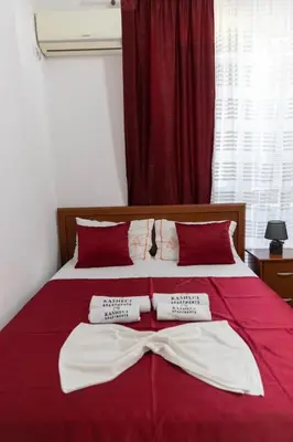 a red bed with two white towels on it at Kasneci Apartments in Ulcinj