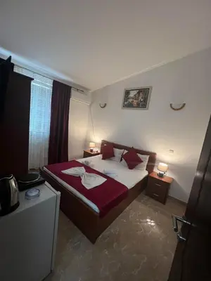 a bedroom with a bed with red sheets and pillows at Kasneci Apartments in Ulcinj