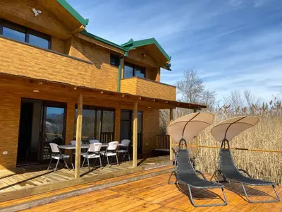 a deck with chairs and a table on a house at Lake River House Ada Bojana in Ulcinj