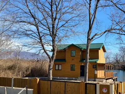 a wooden house with a fence and trees at Lake River House Ada Bojana in Ulcinj