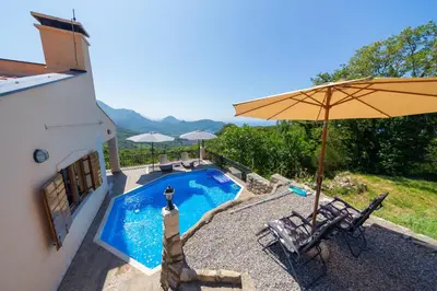 a swimming pool with an umbrella and two chairs at Villa Robinson in Petrovac na Moru