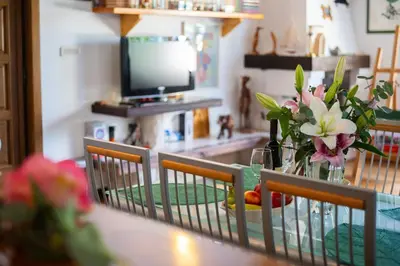 a dining room table with a vase of flowers and a television at Villa Robinson in Petrovac na Moru