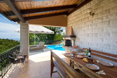 an outdoor patio with a table and a swimming pool at Villa Robinson in Petrovac na Moru