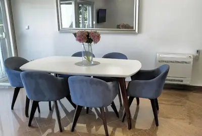 a white table with blue chairs and a vase of flowers at Lux Pržno View Penthouse in Budva