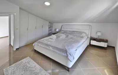 a white bedroom with a bed and a night stand at Lux Pržno View Penthouse in Budva