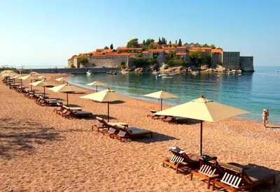 a row of umbrellas and chairs on a beach at Lux Pržno View Penthouse in Budva