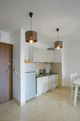 a kitchen with white cabinets and a table and chairs at Anatolia - Family Sea View one-bedroom apartment in Budva