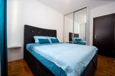 a bedroom with a bed with blue sheets and a mirror at Lux View in Budva