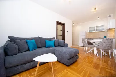a living room with a blue couch and a kitchen at Lux View in Budva