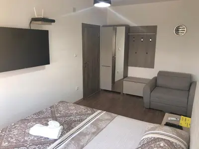 a bedroom with a bed and a chair and a television at Renta stan apartman odmor in Podgorica