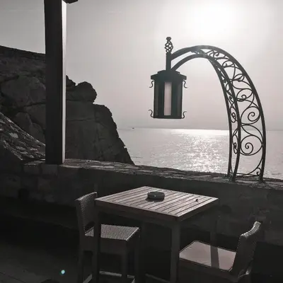 a table and chairs next to the water with a light at Lux View in Petrovac na Moru