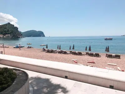a beach with chairs and umbrellas and the ocean at Lux View in Petrovac na Moru