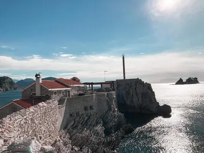 a building on a cliff next to the water at Lux View in Petrovac na Moru