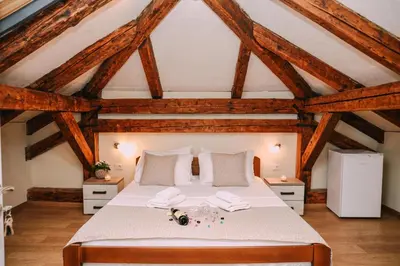 a bedroom with a large white bed with wooden ceilings at Step to Kotor bay Guesthouse in Kotor