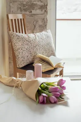 a chair with a book and a bouquet of tulips at Step to Kotor bay Guesthouse in Kotor