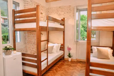 a room with two bunk beds and two windows at Step to Kotor bay Guesthouse in Kotor