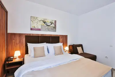 a bedroom with a large white bed and a chair at Hotel La mer in Budva