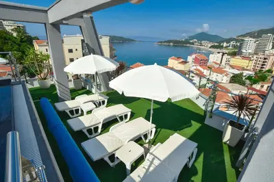 a balcony with white chairs and umbrellas and the water at Hotel La mer in Budva