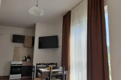 a room with a table and a kitchen with a window at Lucia's Apartment in Sutomore