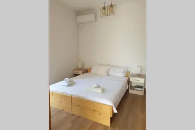 a bedroom with a white bed and a wooden floor at Lucia's Apartment in Sutomore