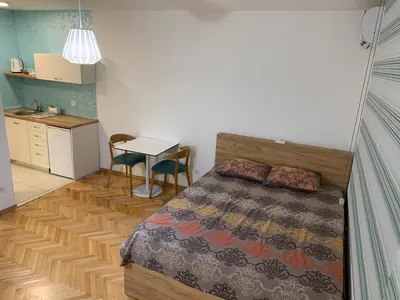 a bedroom with a bed and a table and a kitchen at Clock tower apartments in Podgorica