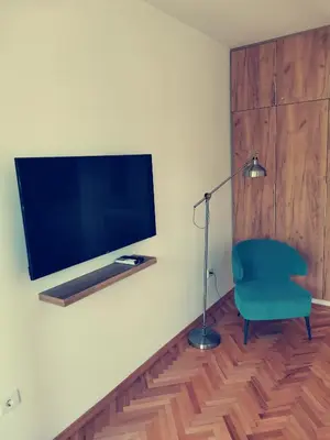 a living room with a green chair and a flat screen tv at Clock tower apartments in Podgorica