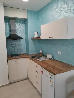 a kitchen with white cabinets and a wooden counter top at Clock tower apartments in Podgorica