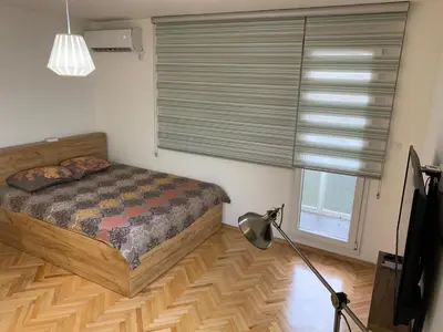 a bedroom with a bed and a window with blinds at Clock tower apartments in Podgorica
