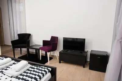 a room with a bed and chairs and a tv at Studio apartment Vukcevic 2 in Podgorica
