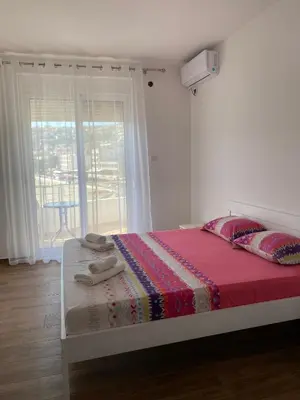 a bedroom with a bed with a red blanket and a window at Seafront Apartments in Ulcinj