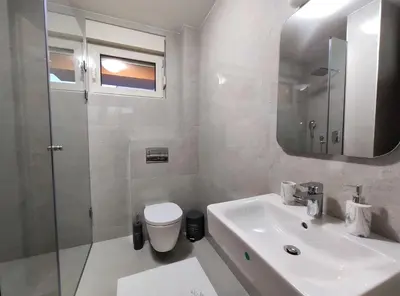 a bathroom with a sink and a toilet and a mirror at Kala Rooms & Suites in Budva