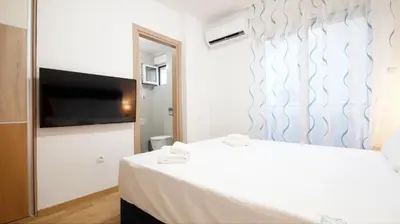 a bedroom with a bed and a flat screen tv at Kala Rooms & Suites in Budva