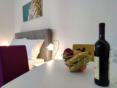 a bottle of wine and a bowl of fruit on a table at Kala Rooms & Suites in Budva