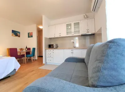 a living room with a blue couch and a kitchen at Kala Rooms & Suites in Budva