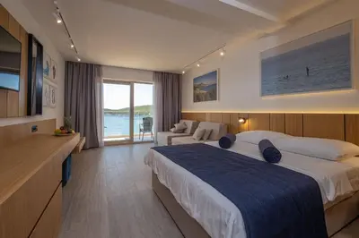 a hotel room with a large bed and a couch at Poseidon The Beach Hotel in Budva