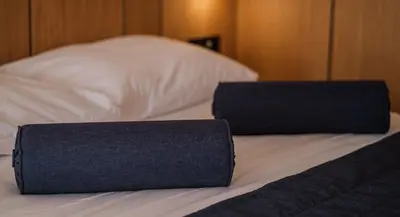 a bed with two blue pillows on top of it at Poseidon The Beach Hotel in Budva