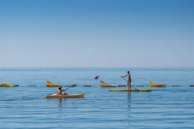 two people are in the water on kayaks in the ocean at Poseidon The Beach Hotel in Budva